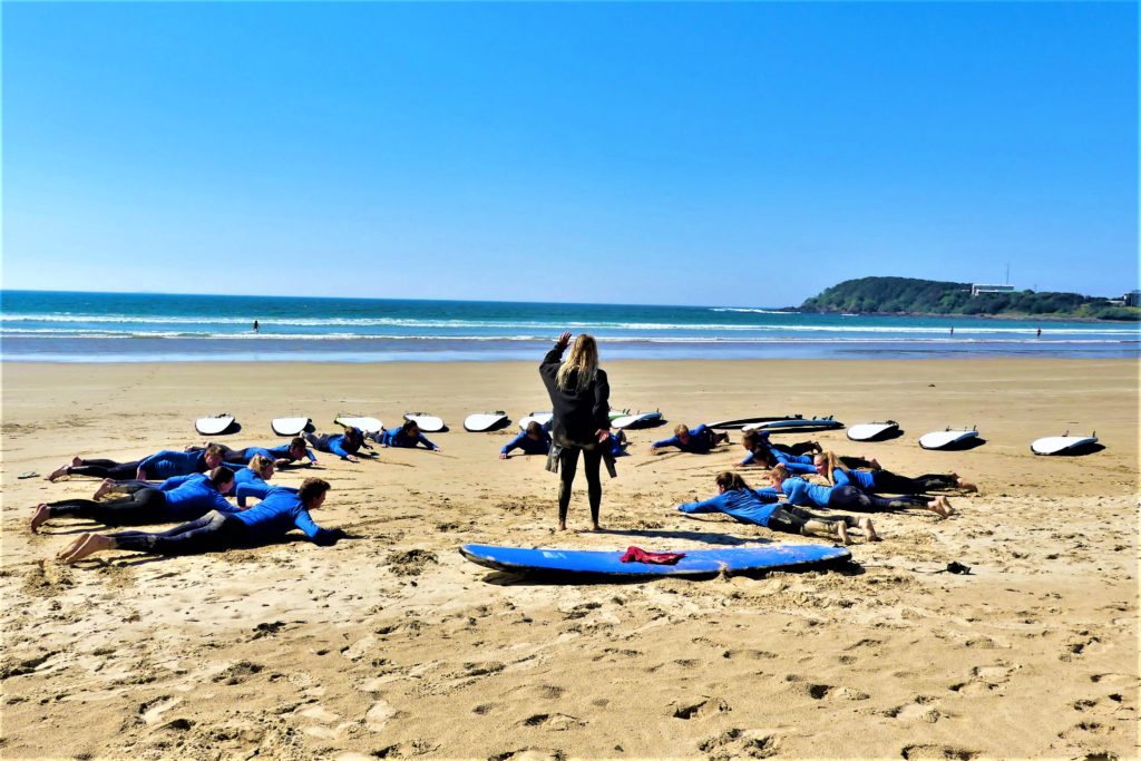 Instructor teaching new surfers on the beach